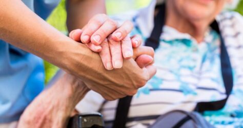 Nurse consoling senior woman holding her hand